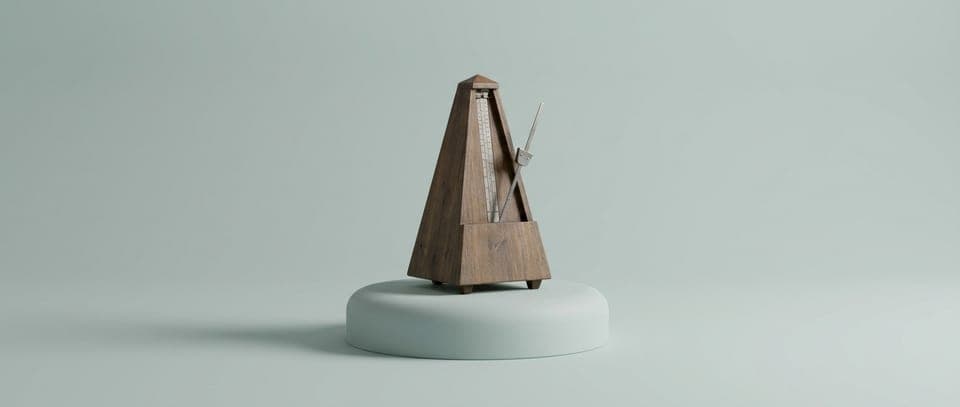 A wooden metronome on a grey-green plinth