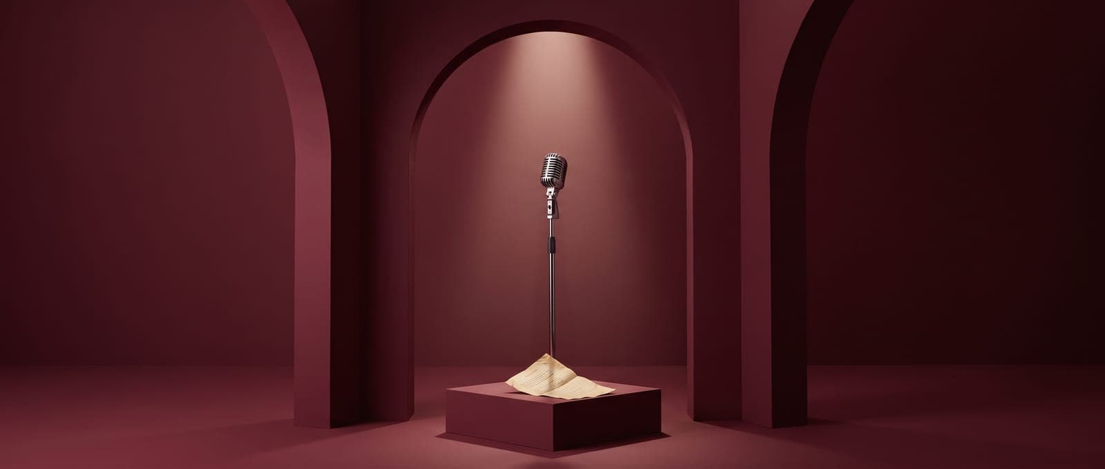A chrome microphone under a spotlight inside a deep red arch